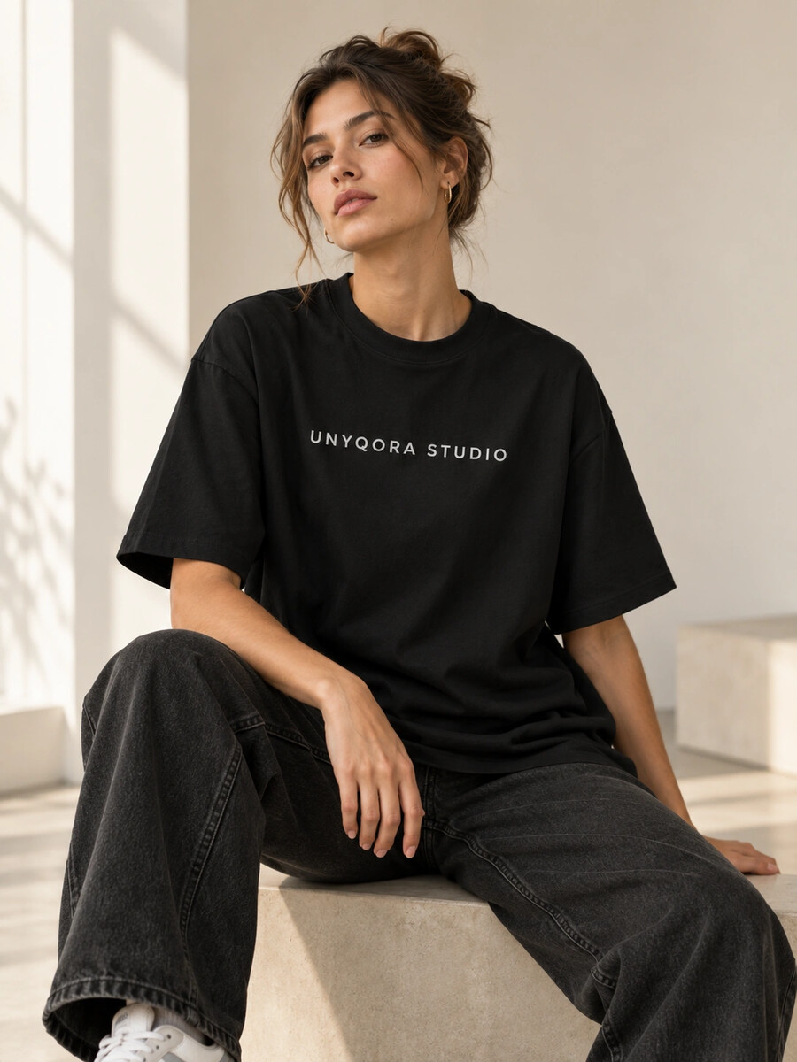 Trendiges Streetwear-Porträt einer jungen Frau in schwarzem Oversize-T-Shirt mit Studio-Look